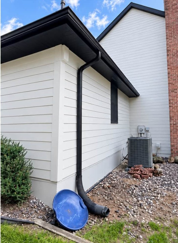 Home exterior after repaint, white siding with black gutters